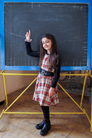 Photo for Student in front of a blackboard in a class in a school, indicates a point - Royalty Free Image