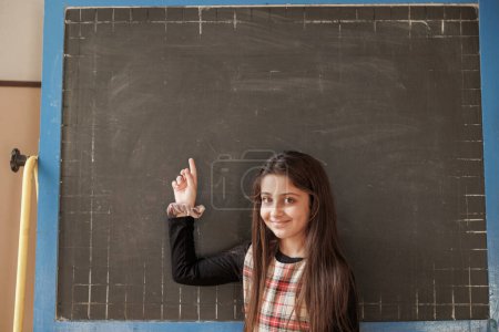 Photo for Young female student points at a blank blackboard - Royalty Free Image