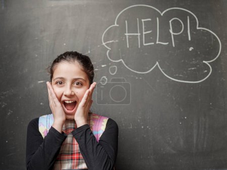 Photo for Young student screams with hands in face - in the background on a blackboard is written the word "Help" - Royalty Free Image