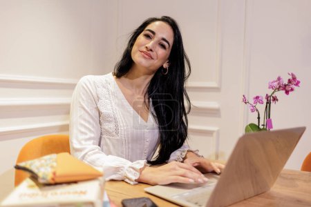 Photo for Woman working with a computer and books in a home office - Royalty Free Image