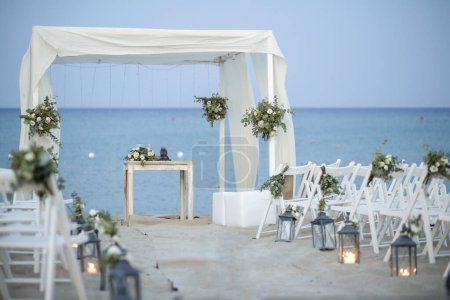 Téléchargez les photos : Décor de mariage avec des fleurs et des lanternes sur la plage - en image libre de droit