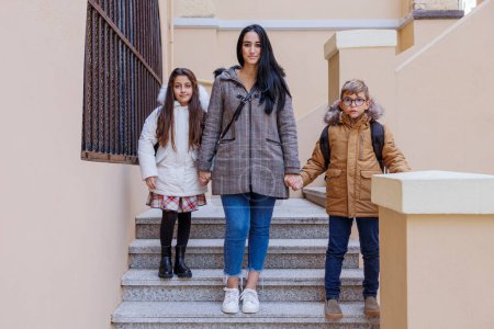 Photo for A mother with black hair takes her two children to school - Royalty Free Image