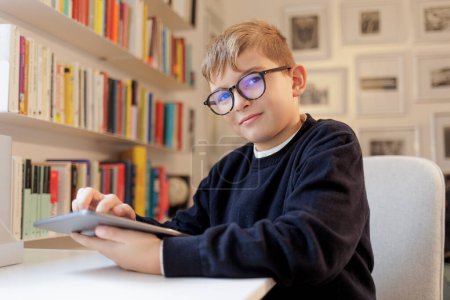 Foto de Retrato del estudiante sentado frente a su escritorio usando su tableta - Imagen libre de derechos