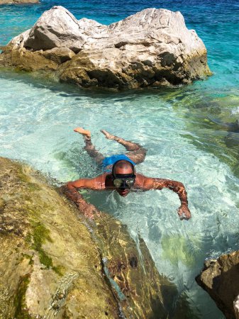 Photo for A man with a diving mask in the shallow waters of a cove in Sardinia - Royalty Free Image