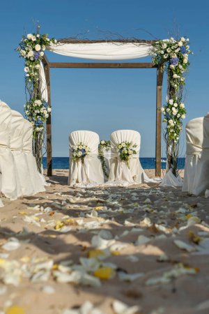 Téléchargez les photos : Arche de mariage décorée de belles fleurs sur la plage - en image libre de droit