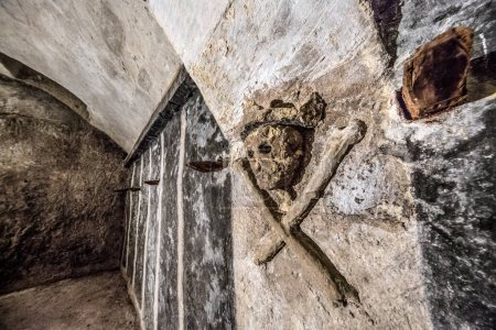 Foto de Cripta de San Sepolcro Cagliari detalle de cráneo coronado engastado en las paredes con huesos cruzados - Imagen libre de derechos