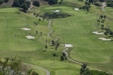 Téléchargez les photos : Terrain de golf avec herbe verte au milieu d'une route de campagne dans les montagnes - en image libre de droit