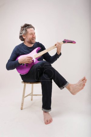 man practicing guitar sitting down studio shoot