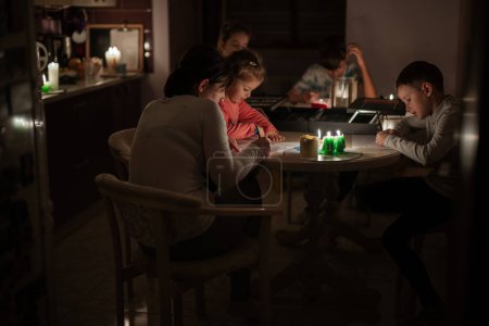 Téléchargez les photos : Les familles passent du temps ensemble pendant une crise énergétique en Europe provoquant des pannes d'électricité. Les enfants dessinent dans le blackout. - en image libre de droit