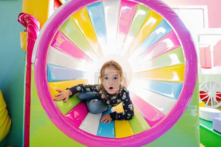 Foto de Chica divertida jugando en el patio interior del centro de juego en tubo de color. - Imagen libre de derechos