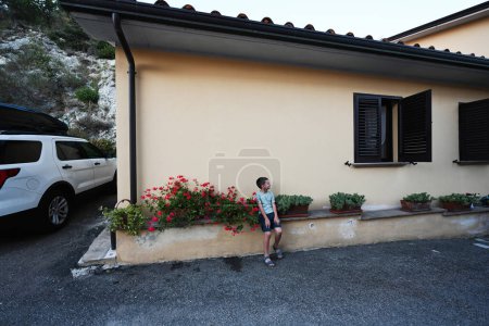 Foto de Niño sentarse cerca de casa en Nocera Umbra, ciudad y municipio en la provincia de Perugia, Italia. - Imagen libre de derechos
