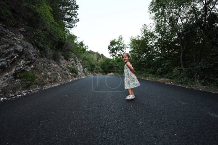 Téléchargez les photos : Bébé fille courir dans la route de montagne de Nocera Umbra, ville et commune dans la province de Pérouse, Italie. - en image libre de droit