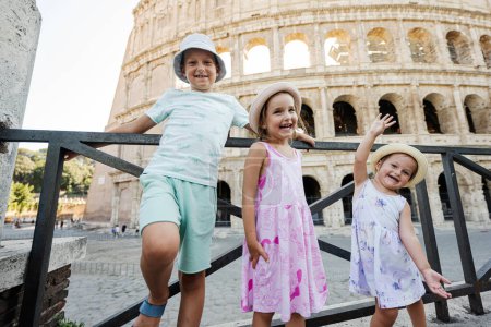Foto de Tres niños divertidos contra el Coliseo en el casco antiguo de Roma, Italia. - Imagen libre de derechos