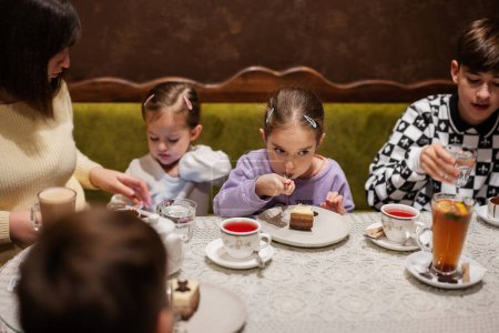 Téléchargez les photos : Bonne famille manger des desserts ensemble au café confortable et avoir du plaisir. - en image libre de droit