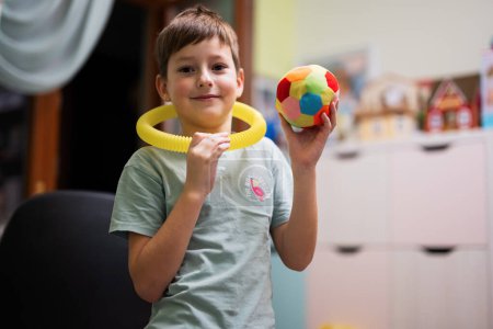 Foto de Boy wore tube on neck with ball in hand at children's room. - Imagen libre de derechos