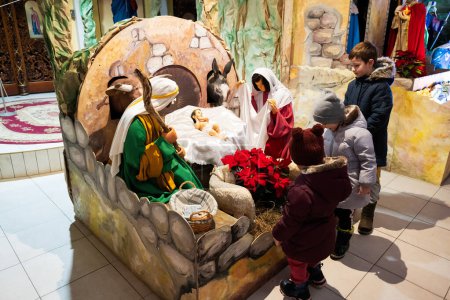 Foto de Christmas nativity crib scene in church. Kids visit stable with baby Jesus in a manger, Mary and Joseph. - Imagen libre de derechos