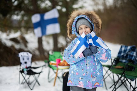 Finnisches kleines Mädchen mit Finnland-Flaggen an einem schönen Wintertag. Skandinavische Menschen. 