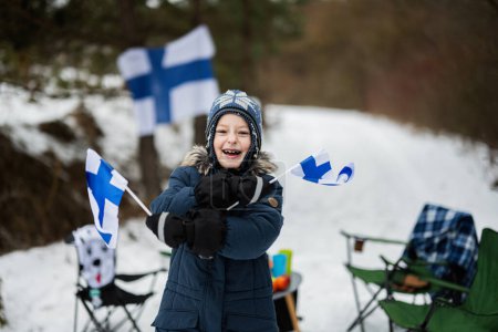 Finnischer Junge mit Finnland-Fahnen an einem schönen Wintertag. Skandinavische Menschen. 