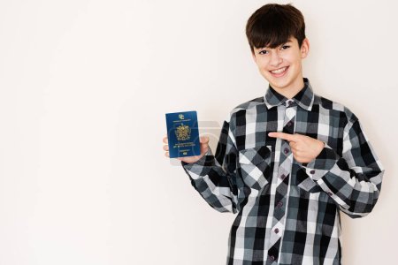 Photo for Young teenager boy holding Saint Kitts and Nevis passport looking positive and happy standing and smiling with a confident smile against white background. - Royalty Free Image