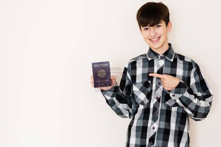 Foto de Young teenager boy holding Uzbekistan passport looking positive and happy standing and smiling with a confident smile against white background. - Imagen libre de derechos