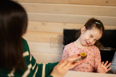 Foto de Madre con hija come frutas, ella dio una fruta de la pasión. Muchacha con muecas por el sabor amargo. - Imagen libre de derechos