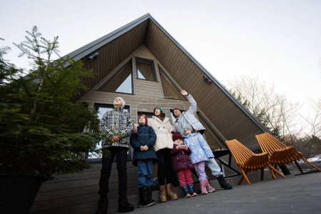 Téléchargez les photos : Grande famille avec quatre enfants sur terrasse hors réseau minuscule maison dans les montagnes. - en image libre de droit