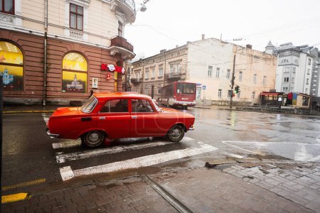 Photo for Ivano-Frankivsk, Ukraine - March, 2023: Red Moskvich AZLK Soviet classic retro car driving on rainy street. - Royalty Free Image