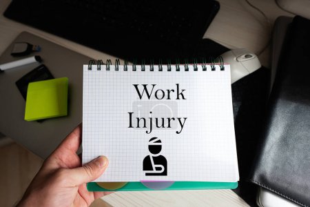 Photo for Work injury word on notebook holding man against desktop. - Royalty Free Image