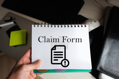 Photo for Claim form word on notebook holding man against desktop. - Royalty Free Image