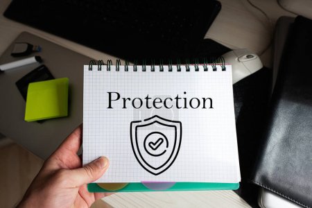 Photo for Protection word on notebook holding man against desktop. - Royalty Free Image