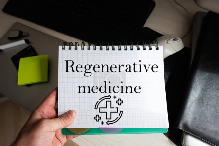 Foto de Palabra de medicina regenerativa en portátiles que sostiene al hombre contra el escritorio. - Imagen libre de derechos