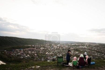Photo for Family hiking on vacation, having evening picnic on top of the mountain, looking at beautiful canyon landscape. - Royalty Free Image