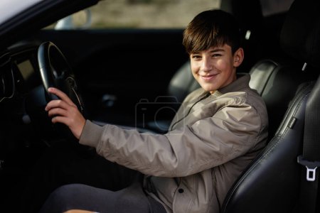 Téléchargez les photos : Adolescent garçon assis dans la voiture musculaire. Jeune adolescent conducteur. - en image libre de droit