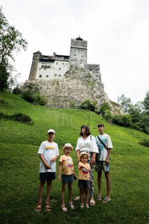 Foto de Turistas familiares contra el Castillo de Bran en Rumania. Castillo medieval de Drácula en Cárpatos, Transilvania. - Imagen libre de derechos
