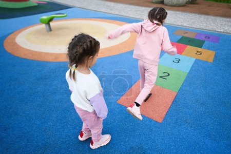 Photo for Back view of two girls playing hopscotch game at playground - Royalty Free Image