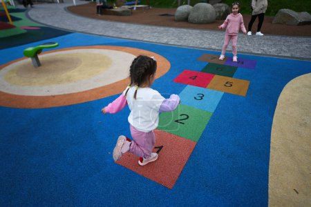 Photo for Cute little girl playing hopscotch game in the playground. - Royalty Free Image