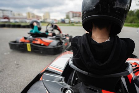 Primer plano de una persona enfocada en un casco negro conduciendo un go-kart durante una carrera intensa. Experimenta la emoción y la emoción de las carreras de karts.