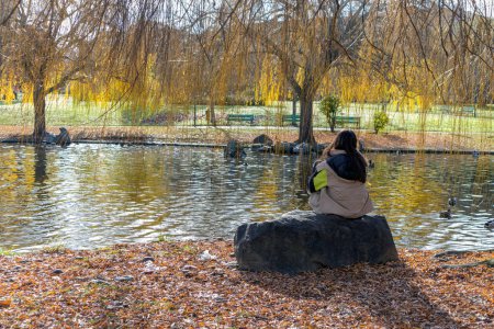 Foto de Woman seen from behind sitting in city park - Imagen libre de derechos