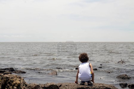 Téléchargez les photos : Little boy looking at polluted river from the shore, environmental concept - en image libre de droit