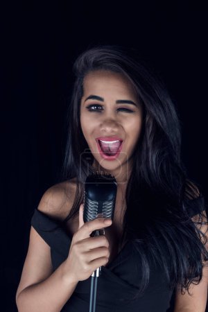 A lively black female singer performing with a retro microphone.