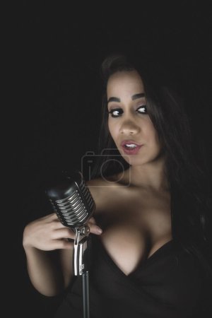 A jazz singer captivates with a sultry look, holding a vintage mic.