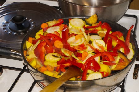Téléchargez les photos : Homemade cooking of mixed fried vegetables comprising red peppers, potatoes, courgettes and carrots in a stovepan - en image libre de droit
