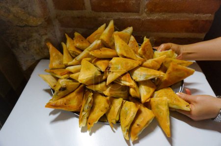 Foto de Bandeja de samosas artesanales caseras; una samosa es un pastel frito tradicional de Oriente (especialmente de la India y el sudeste asiático), relleno con un relleno salado y generalmente en forma triangular - Imagen libre de derechos