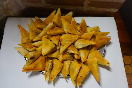 Photo for Tray of homemade artisanal samosas ; a samosa is a traditional fried pastry from the Orient (especially from India and Southeast Asia), stuffed with a savoury filling and usually triangular-shaped - Royalty Free Image