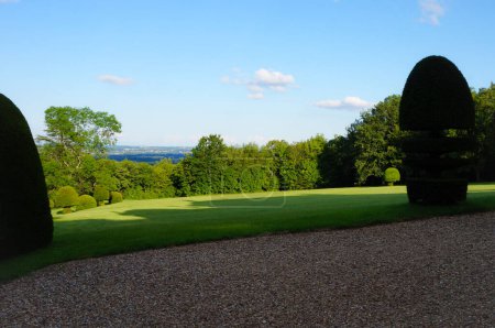 Foto de Parque verde con tierra de grava en primer plano, arbustos recortados, césped verde y vista sobre el Valle de Sane, en la región de Beaujolais, en el fondo más allá del bosque, con colinas en el horizonte - Imagen libre de derechos
