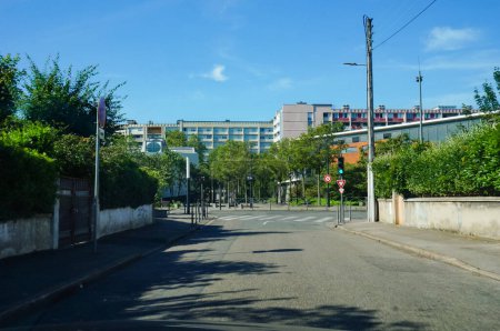 Téléchargez les photos : Une rue bordée d'arbres et des blocs de bâtiments (logements sociaux) dans un quartier résidentiel populaire de Bron, une ville à la périphérie de la zone urbaine de Lyon, la deuxième plus grande ville de France - en image libre de droit