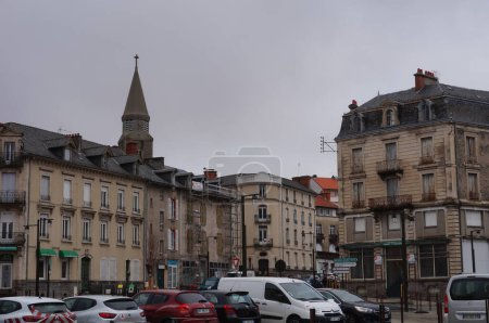 Foto de Aurillac, Francia - Feb. 2022 - Casas adosadas en la Plaza Pierre Semard, frente a la estación de tren, con la torre de la Iglesia Sacre-Coeur en el fondo; Aurillac es la ciudad principal del Cantal - Imagen libre de derechos
