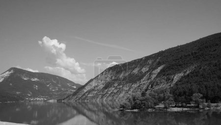 Foto de Foto en blanco y negro de un hermoso paisaje montañoso en los Alpes provenzales franceses (Alta Provenza) con acantilados rocosos cubiertos de árboles reflejados en el agua del lago de Castillon, en las gargantas del Verdon - Imagen libre de derechos
