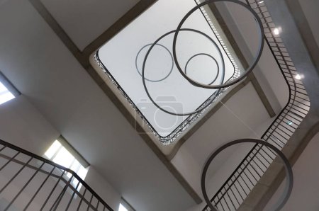 Foto de Toulouse, Francia - Nov. 2019 - Araña monumental en forma de anillos superpuestos colgados en el techo de la enorme escalera del recién restaurado edificio jacobino de Pierre de Fermat Lycee - Imagen libre de derechos