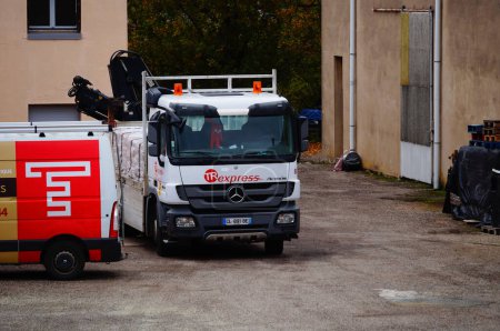 Foto de Albi, Francia - Dec. 2021 - Un camión de cama plana Mercedes-Benz Actros, equipado con una grúa plegable montada en la parte trasera, en una entrega de mercancías para una empresa de construcción, fuera de una fábrica industrial - Imagen libre de derechos